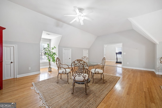 dining space with light wood-style floors, baseboards, vaulted ceiling, and a ceiling fan