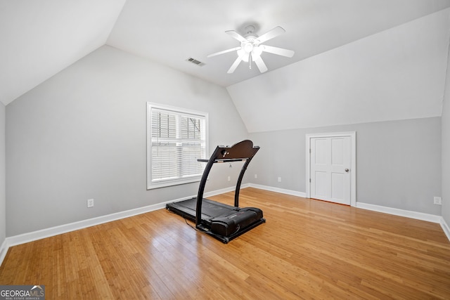 workout area featuring baseboards, visible vents, vaulted ceiling, and wood finished floors