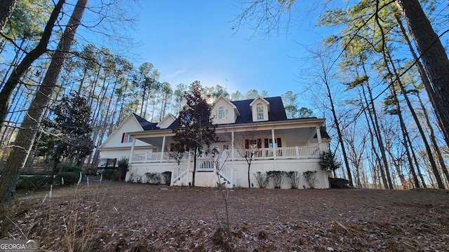 back of property featuring covered porch and stairs