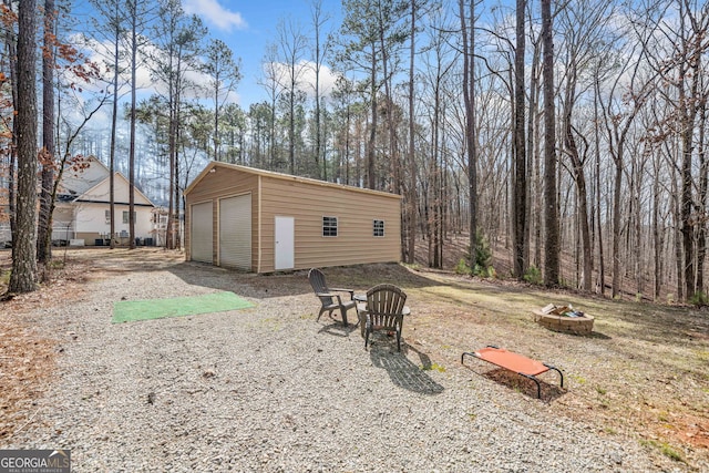 exterior space featuring an outdoor structure, a garage, and an outdoor fire pit