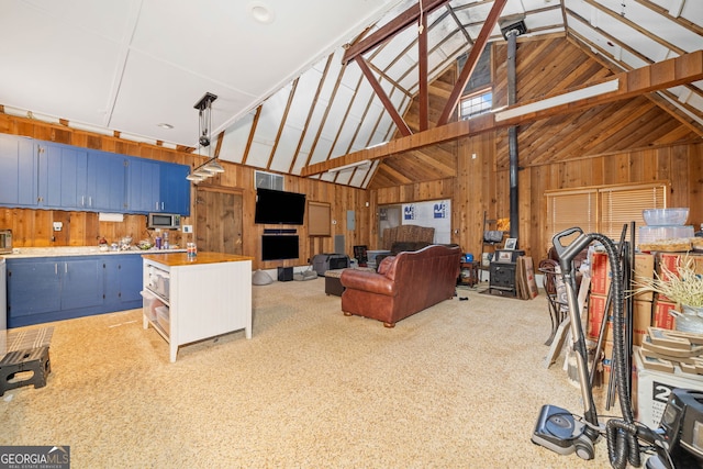 living area with high vaulted ceiling, wooden walls, and carpet flooring