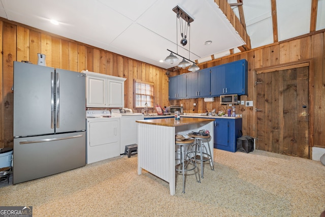 kitchen with an island with sink, stainless steel appliances, blue cabinetry, a kitchen bar, and pendant lighting