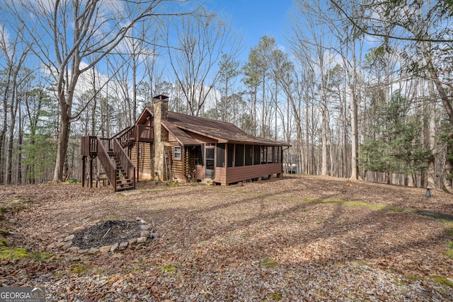 view of side of home featuring roof with shingles, stairway, a chimney, and a sunroom