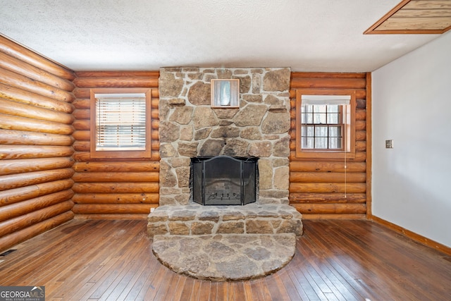 living area featuring a textured ceiling, baseboards, dark wood-style flooring, and a stone fireplace