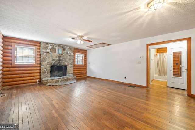 unfurnished living room featuring visible vents, rustic walls, a textured ceiling, and wood finished floors