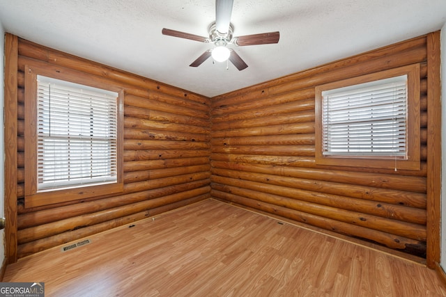 empty room with light wood-type flooring, a ceiling fan, visible vents, and a textured ceiling