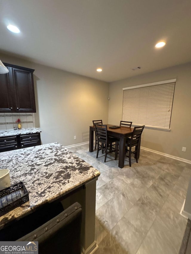 interior space with light stone countertops, backsplash, and dark brown cabinetry