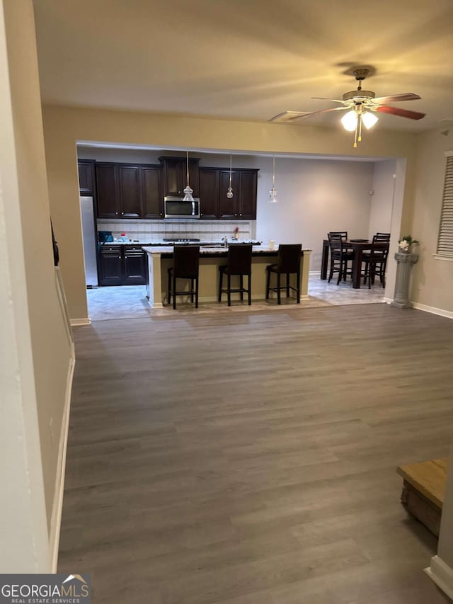 kitchen featuring a kitchen island, a breakfast bar, refrigerator, dark brown cabinetry, and light hardwood / wood-style flooring