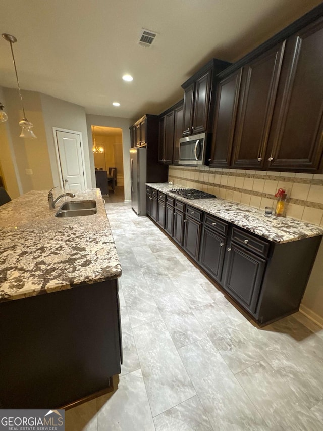 kitchen featuring appliances with stainless steel finishes, tasteful backsplash, sink, hanging light fixtures, and dark brown cabinets