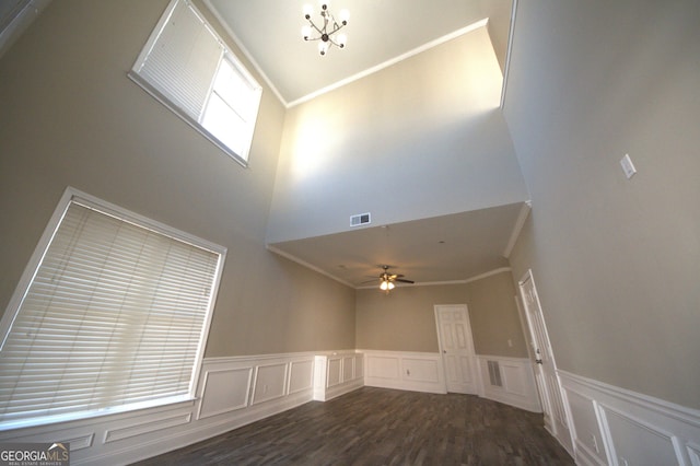 interior space featuring ornamental molding, dark wood-type flooring, and ceiling fan with notable chandelier