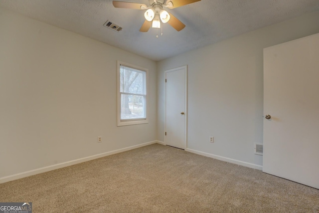 empty room with light carpet, a textured ceiling, and ceiling fan