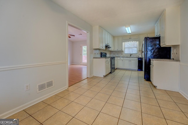 kitchen with black appliances, sink, light tile patterned floors, tasteful backsplash, and white cabinetry