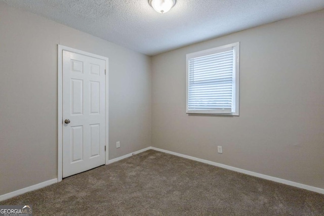 carpeted empty room with a textured ceiling