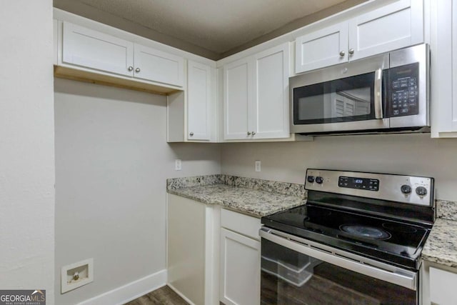 kitchen featuring white cabinets, light stone counters, stainless steel appliances, and hardwood / wood-style floors