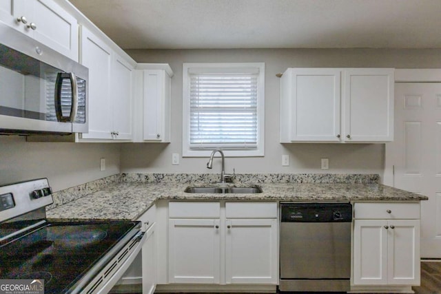 kitchen with white cabinetry, sink, light stone countertops, and appliances with stainless steel finishes