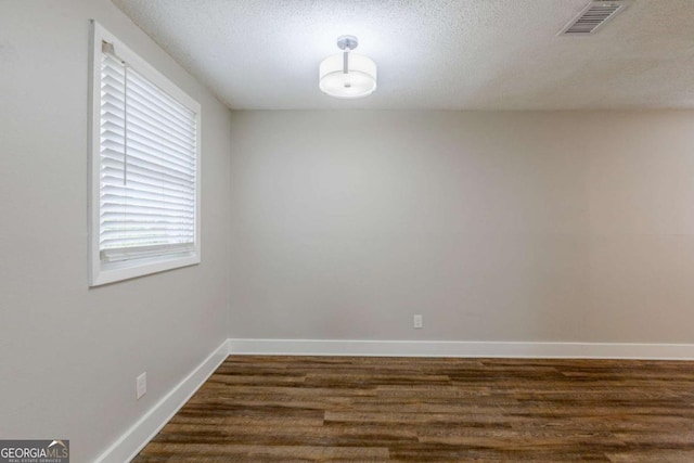 spare room featuring a textured ceiling and dark wood-type flooring