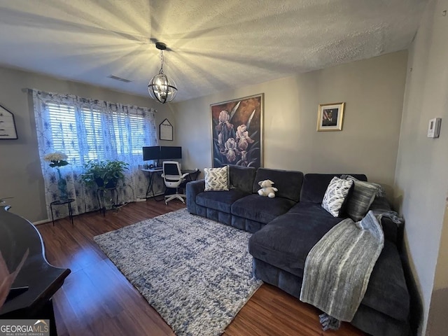 living room featuring dark hardwood / wood-style floors, a notable chandelier, and a textured ceiling