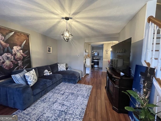 living room featuring an inviting chandelier, a textured ceiling, and dark hardwood / wood-style flooring