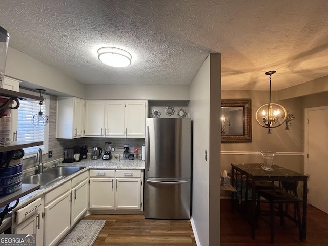 kitchen featuring stainless steel refrigerator, sink, tasteful backsplash, and white cabinets