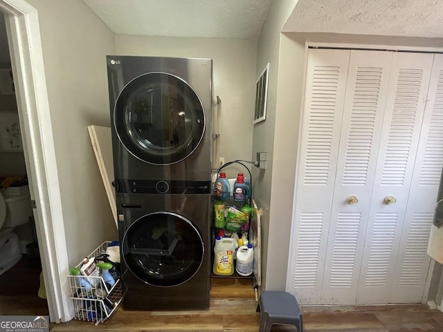 clothes washing area featuring stacked washer and clothes dryer and a textured ceiling