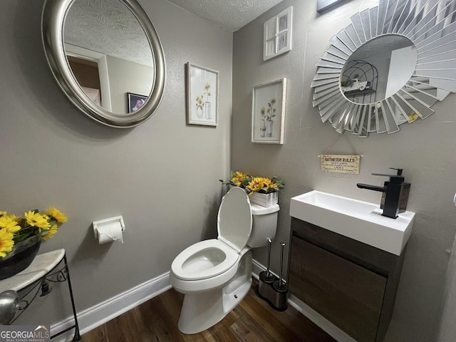 bathroom with vanity, toilet, wood-type flooring, and a textured ceiling