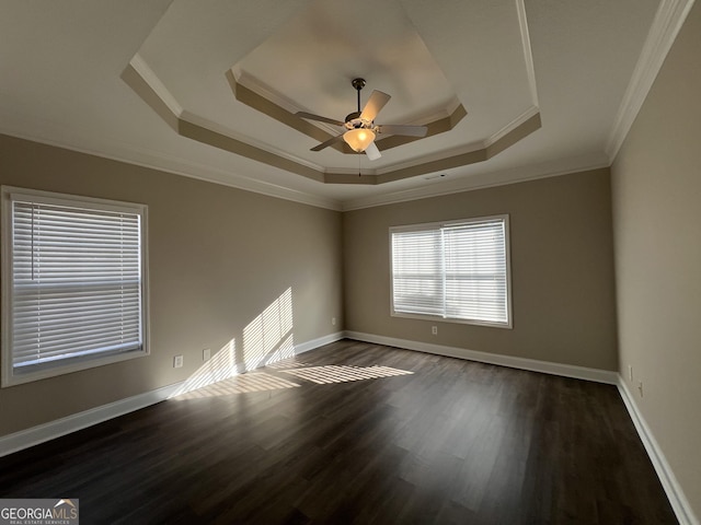 spare room with ceiling fan, ornamental molding, dark wood-type flooring, and a tray ceiling