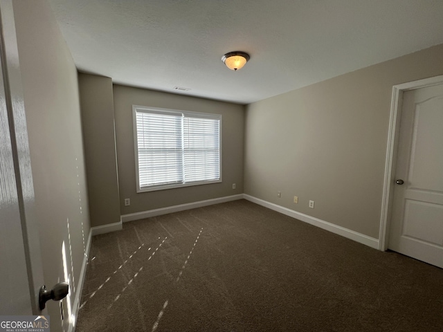 unfurnished room with dark colored carpet