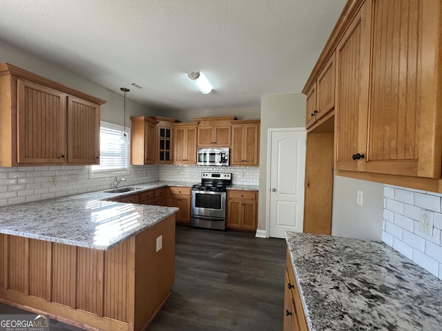 kitchen featuring sink, hanging light fixtures, tasteful backsplash, light stone counters, and stainless steel appliances