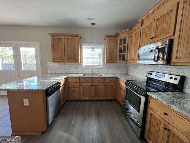 kitchen with light stone countertops, sink, hanging light fixtures, dark hardwood / wood-style flooring, and appliances with stainless steel finishes