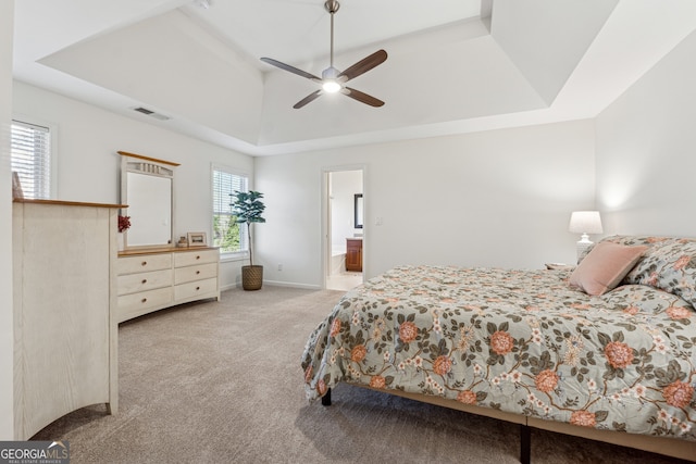 carpeted bedroom featuring a towering ceiling, ensuite bath, a raised ceiling, and ceiling fan