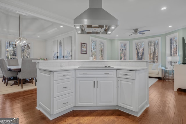 kitchen with island exhaust hood, white cabinetry, a center island, and ceiling fan with notable chandelier