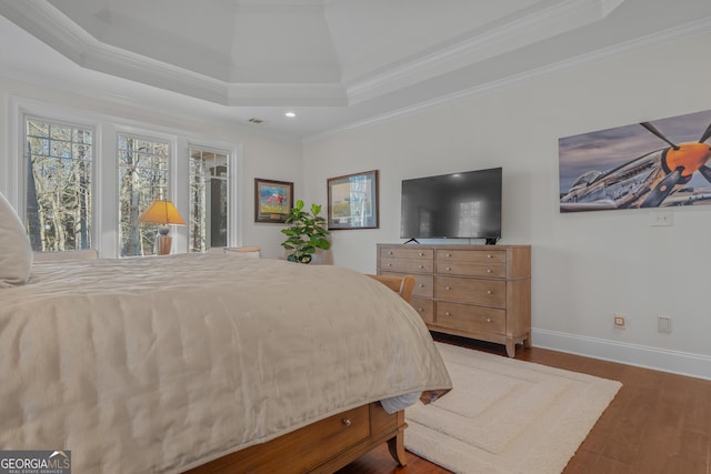 bedroom with a raised ceiling, crown molding, and dark hardwood / wood-style floors