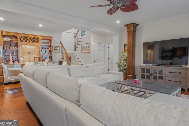 living room featuring bar area, ceiling fan, ornamental molding, ornate columns, and light hardwood / wood-style floors