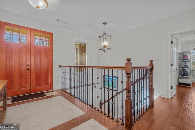 foyer entrance featuring a chandelier, ornamental molding, and light tile patterned flooring