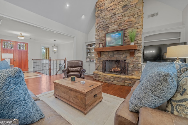 living room with a fireplace, light hardwood / wood-style flooring, high vaulted ceiling, and built in shelves