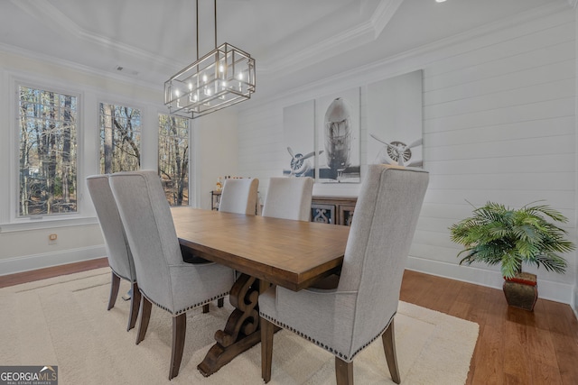 dining space featuring light wood-type flooring, ornamental molding, and a tray ceiling