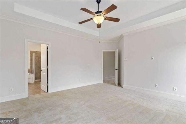 unfurnished room with a raised ceiling, ceiling fan, light colored carpet, and crown molding