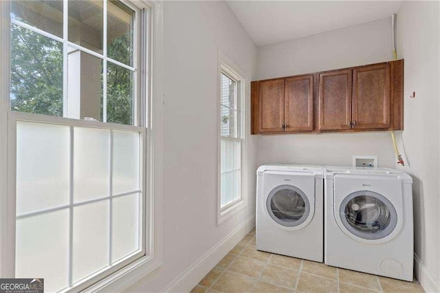 clothes washing area featuring cabinets, light tile patterned floors, and washing machine and dryer