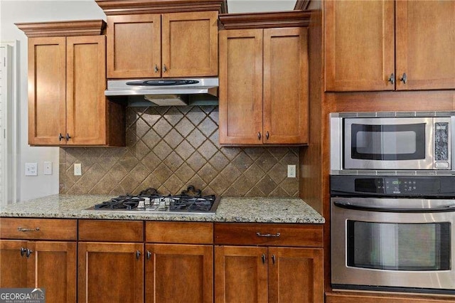 kitchen featuring light stone countertops, appliances with stainless steel finishes, and tasteful backsplash