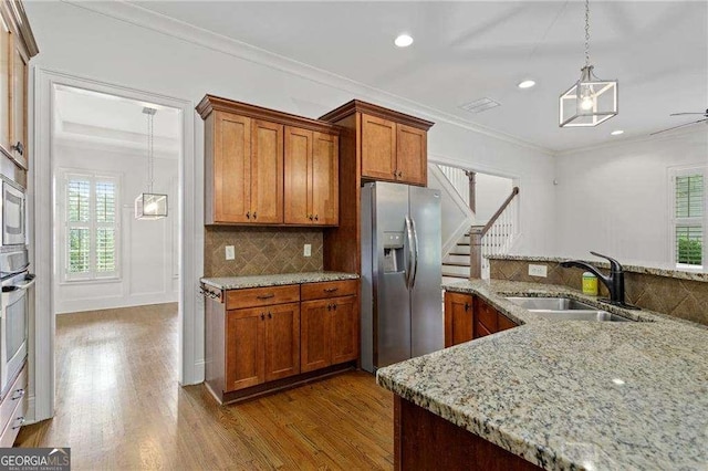 kitchen with light stone counters, sink, stainless steel appliances, and crown molding