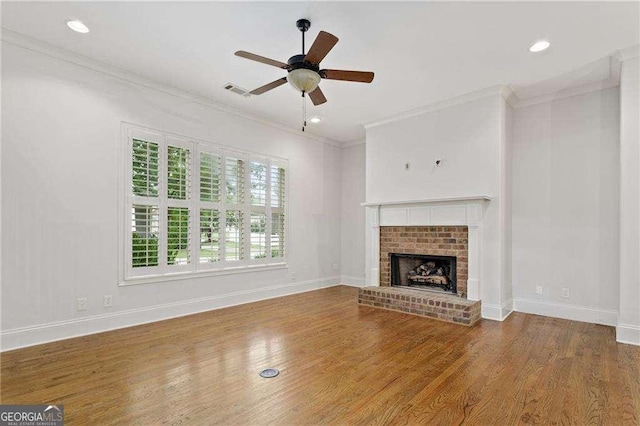 unfurnished living room featuring crown molding, a fireplace, ceiling fan, and hardwood / wood-style flooring