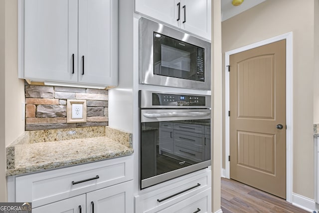 kitchen featuring built in microwave, white cabinetry, oven, and decorative backsplash