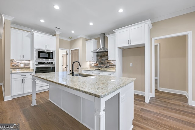 kitchen featuring wall chimney range hood, sink, white cabinets, and stainless steel oven