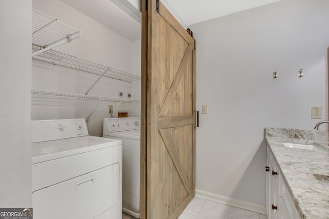 clothes washing area featuring washer and dryer, a barn door, and sink