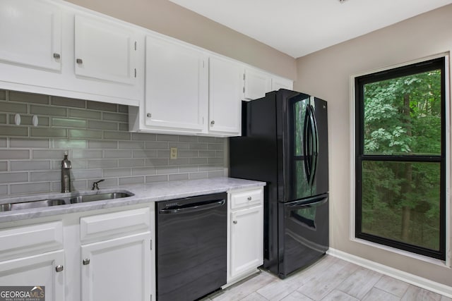 kitchen with tasteful backsplash, light stone counters, sink, black appliances, and white cabinets