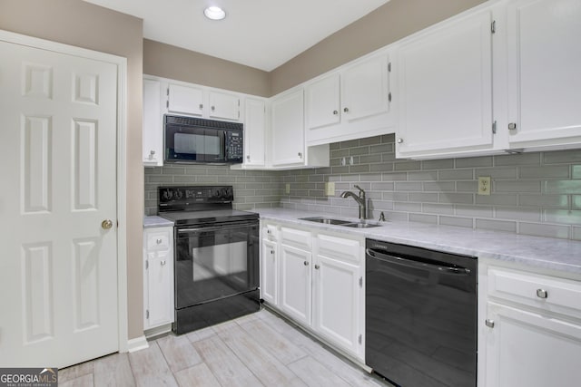 kitchen featuring sink, light hardwood / wood-style floors, decorative backsplash, white cabinets, and black appliances