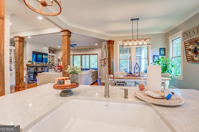 kitchen with decorative columns, plenty of natural light, hanging light fixtures, and ornamental molding