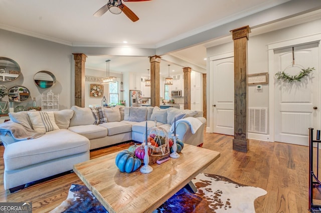 living room featuring decorative columns, hardwood / wood-style flooring, ornamental molding, and ceiling fan