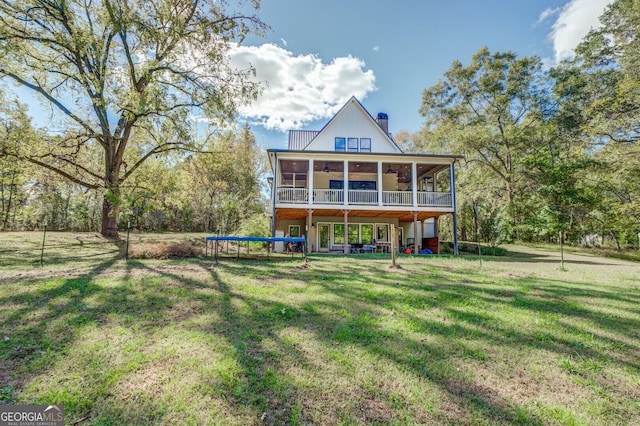 back of house featuring a yard, a trampoline, and a sunroom