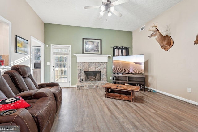 living room with a fireplace, ceiling fan, wood-type flooring, and a textured ceiling